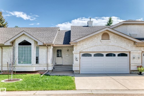 Front exterior featuring textured stucco siding, a gabled roofline, and an integrated garage - 50 303 Twin Brooks Drive Nw, Edmonton, AB 