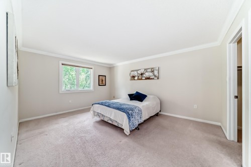 Carpeted room featuring a window with exterior tree scenery, crown molding, baseboards, and a recessed closet with shelving - 50 303 Twin Brooks Drive Nw, Edmonton, AB 