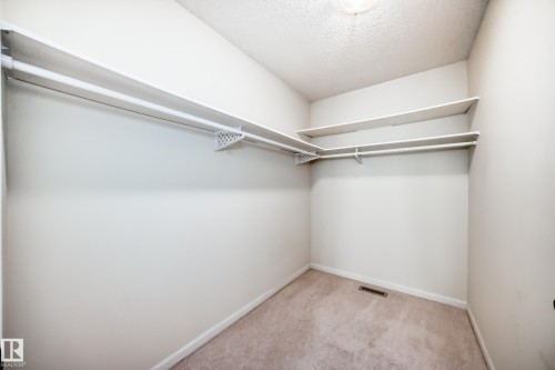 Walk-in closet featuring white walls, light-colored carpeting, multiple shelving units, and clothing rods - 50 303 Twin Brooks Drive Nw, Edmonton, AB 