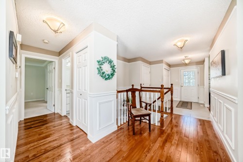 Hardwood flooring extending through the hallway, featuring wainscoting and crown molding - 50 303 Twin Brooks Drive Nw, Edmonton, AB 