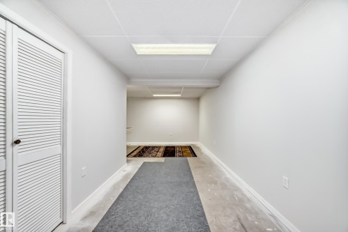Finished room featuring a drop ceiling, louvered bi-fold door, recessed fluorescent lighting, and a neutral color palette - 50 303 Twin Brooks Drive Nw, Edmonton, AB 