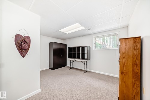 Carpeted room featuring a drop ceiling with recessed lighting, a window with security bars, and white painted walls with white trim - 50 303 Twin Brooks Drive Nw, Edmonton, AB 