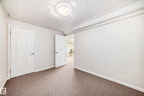 Finished interior space featuring two white paneled doors, neutral wall paint, and a textured drop ceiling - 50 303 Twin Brooks Drive Nw, Edmonton, AB 