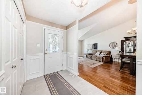 Entryway featuring a decorative glass paneled door, wainscoting, and tile flooring - 50 303 Twin Brooks Drive Nw, Edmonton, AB 