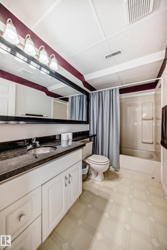 Bathroom featuring a single vanity with a dark countertop and undermount sink, white cabinetry, a large mirror, and overhead lighting - 50 303 Twin Brooks Drive Nw, Edmonton, AB 