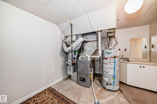 Utility room featuring a water heater, furnace, and a built-in countertop with sink and cabinetry - 50 303 Twin Brooks Drive Nw, Edmonton, AB 