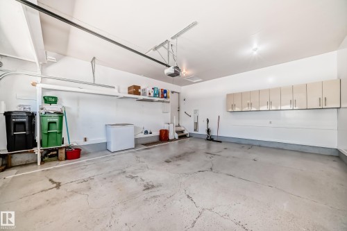 Spacious garage featuring a durable concrete floor, overhead door opener, and built-in cabinetry for organized storage - 50 303 Twin Brooks Drive Nw, Edmonton, AB 