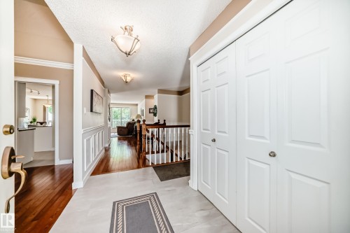 Entryway featuring light-toned flooring, white bi-fold closet doors, and contrasting wood-finish flooring - 50 303 Twin Brooks Drive Nw, Edmonton, AB 