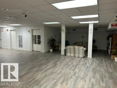 Spacious interior featuring wood-finish flooring, drop ceiling with integrated lighting, multiple white doors, and painted white walls - 50 303 Twin Brooks Drive Nw, Edmonton, AB 