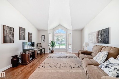 Vaulted ceiling living area featuring hardwood flooring, an arched window, and a bay window configuration - 50 303 Twin Brooks Drive Nw, Edmonton, AB 
