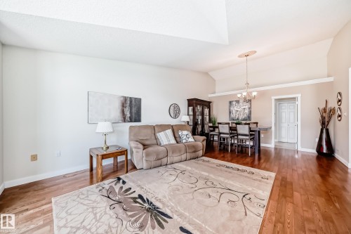 Open-concept living and dining area featuring wood-finish flooring, vaulted ceilings, crown molding, and a chandelier lighting fixture - 50 303 Twin Brooks Drive Nw, Edmonton, AB 