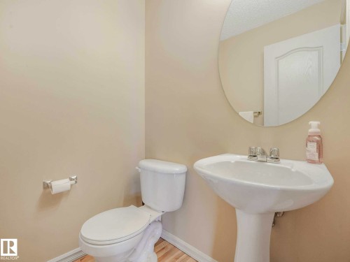 Pedestal sink with chrome fixtures, oval mirror, and light-toned flooring - 1116 Lincoln Crescent, Edmonton, AB - Indoor Photo Showing Bathroom