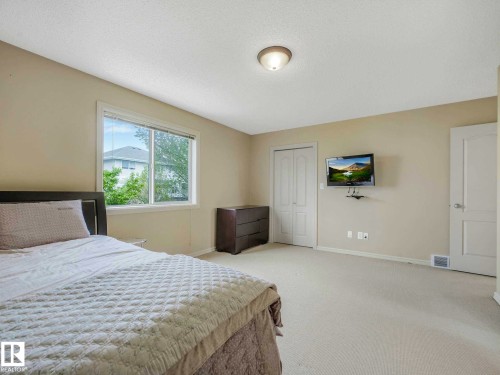 Carpeted room featuring a large window, neutral wall paint, a flush-mount ceiling light, and white paneled doors - 1116 Lincoln Crescent, Edmonton, AB - Indoor Photo Showing Bedroom
