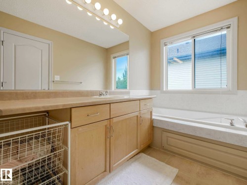 Bathroom featuring a light-toned vanity with integrated sink, a large mirror, and overhead strip lighting - 1116 Lincoln Crescent, Edmonton, AB - Indoor Photo Showing Bathroom