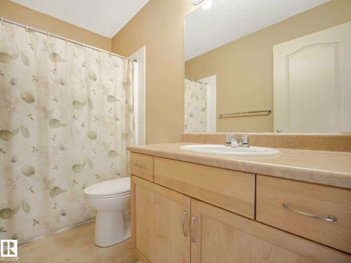Bathroom featuring a light wood-finish vanity with an integrated sink, polished chrome faucet, and a large wall-mounted mirror - 1116 Lincoln Crescent, Edmonton, AB - Indoor Photo Showing Bathroom