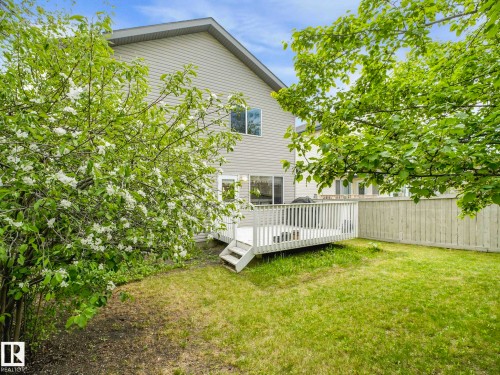 Rear exterior with light-colored siding, a multi-level wood deck, and a grass lawn - 1116 Lincoln Crescent, Edmonton, AB - Outdoor