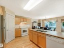 Kitchen featuring wood-finish flooring, light wood cabinetry, white appliances, and an island with a double basin sink - 1116 Lincoln Crescent, Edmonton, AB  - Indoor Photo Showing Kitchen With Double Sink 