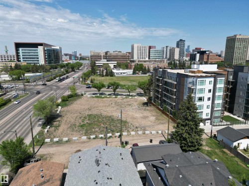 Expansive vacant lot featuring a cleared surface, surrounding commercial and residential buildings, and proximity to a multi-lane roadway - 7915 114 Street Nw, Edmonton, AB 