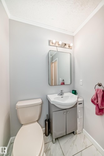 Modern bathroom featuring a vanity with integrated sink, contemporary mirror, and a four-bulb vanity light fixture - 8 Campbell Court, Leduc, AB 