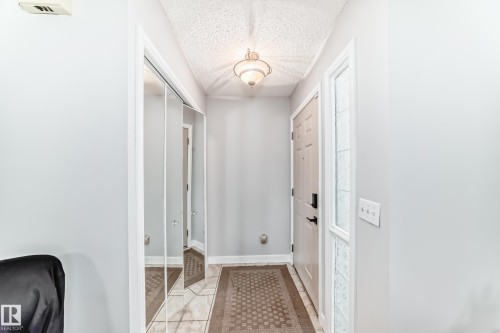 Entryway featuring light gray walls, a textured ceiling, and a ceiling-mounted light fixture - 8 Campbell Court, Leduc, AB 