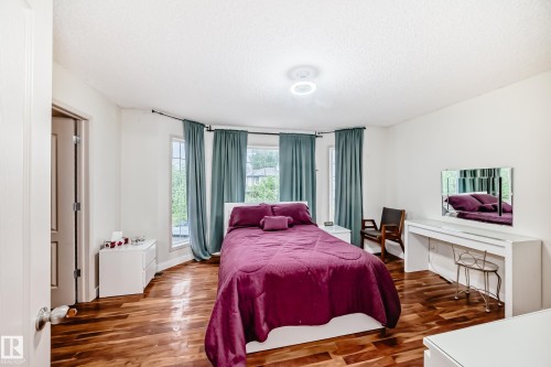 Bedroom featuring wood-finish flooring, white walls, and a recessed bay window - 8 Campbell Court, Leduc, AB 