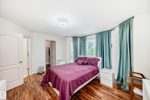 Bedroom featuring wood-finish flooring and a bright window with light blue drapery - 8 Campbell Court, Leduc, AB 