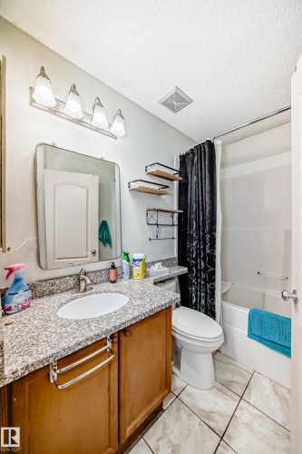 Bathroom featuring a vanity with a granite-style countertop, a rectangular undermount sink, and wood-finish cabinetry - 8 Campbell Court, Leduc, AB 