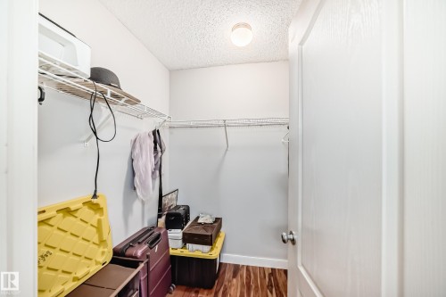 Recessed closet with white wire shelving, hanging rods, light gray walls, and wood-finish flooring - 8 Campbell Court, Leduc, AB 