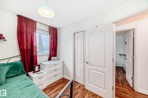 Bedroom featuring wood-finish flooring, a window with natural light, and two white paneled doors - 8 Campbell Court, Leduc, AB 