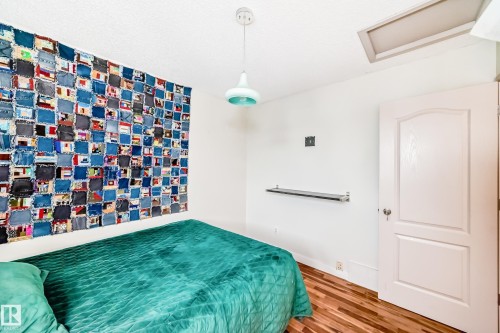 Interior room featuring wood-finish flooring, white walls, and a built-in shelf - 8 Campbell Court, Leduc, AB 