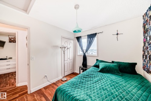 Bedroom featuring wood-finish flooring, a double-panel closet door, a window with exterior views, and a ceiling-mounted light fixture - 8 Campbell Court, Leduc, AB 