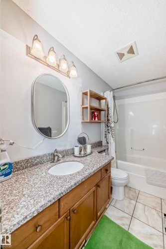 Bathroom featuring a vanity with a granite-finish countertop, undermount sink, and wood-finish cabinetry - 8 Campbell Court, Leduc, AB 