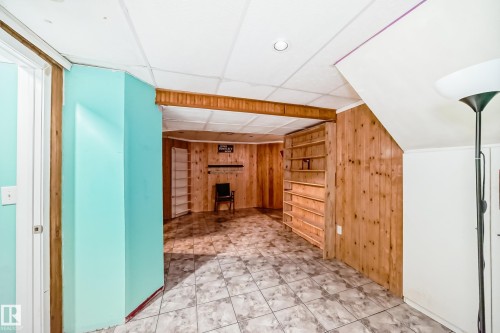 Finished room featuring a drop ceiling with recessed lighting, wood paneling, built-in shelving, and tile flooring - 8 Campbell Court, Leduc, AB 