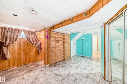Finished interior space featuring wood paneling, built-in shelving, and tiled flooring - 8 Campbell Court, Leduc, AB 