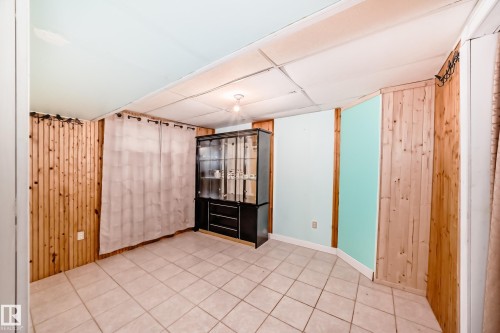 Room featuring light-colored tile flooring, wood paneling, and a drop ceiling with recessed lighting - 8 Campbell Court, Leduc, AB 