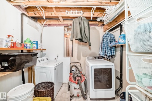 Dedicated laundry area featuring a top-load washing machine, front-load dryer, and overhead exposed ceiling joists - 8 Campbell Court, Leduc, AB 