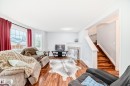 Living area featuring wood-finish flooring, a white mantel, and a tiled fireplace surround - 8 Campbell Court, Leduc, AB 
