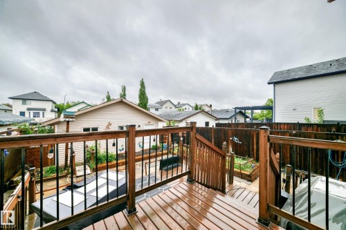 Multi-level wood deck featuring a railing with black metal spindles, wood privacy fencing, and raised garden beds - 8 Campbell Court, Leduc, AB 
