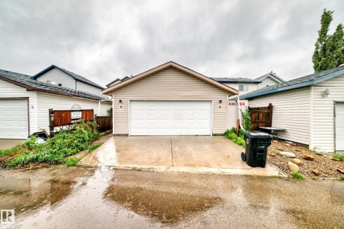 Attached garage with a white panel door and vinyl siding exterior - 8 Campbell Court, Leduc, AB 