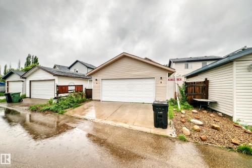 Detached garage with a pitched roof and horizontal siding, featuring a white garage door and concrete driveway - 8 Campbell Court, Leduc, AB 