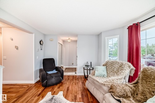 Spacious living area featuring wood-finish flooring, light gray wall paint, and white trim - 8 Campbell Court, Leduc, AB 