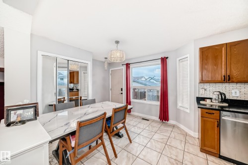 Dining area featuring tiled flooring, a contemporary chandelier, and a bay window - 8 Campbell Court, Leduc, AB 