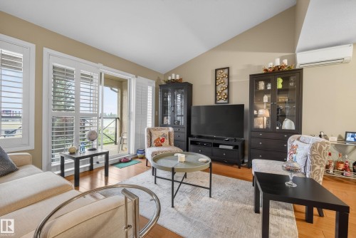 Living area featuring wood-finish flooring, a vaulted ceiling, and neutral-toned walls - 413 8912 156 Street Nw, Edmonton, AB 