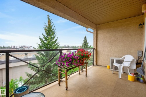 Spacious balcony featuring a glass and wrought iron railing, textured exterior walls, an overhead ceiling, and a concrete flooring surface - 413 8912 156 Street Nw, Edmonton, AB 