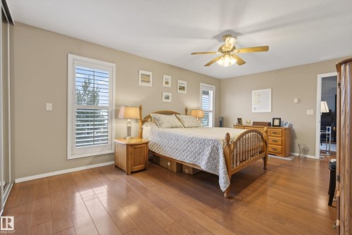 Spacious room featuring wood-finish flooring, neutral-toned walls, and white plantation shutters on windows - 413 8912 156 Street Nw, Edmonton, AB 