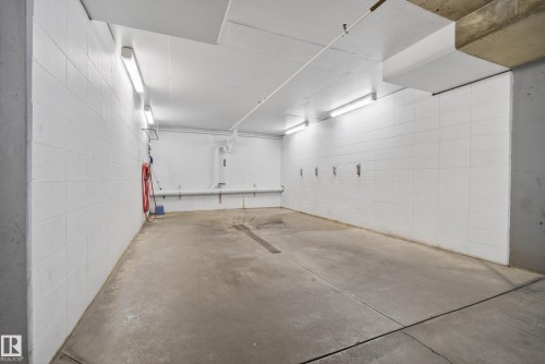 Concrete flooring with drainage channel, white block walls, and overhead fluorescent lighting - 413 8912 156 Street Nw, Edmonton, AB 