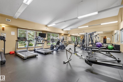 Expansive fitness center featuring a sloped ceiling, recessed lighting, floor-to-ceiling mirrors, large windows, and robust rubber flooring - 413 8912 156 Street Nw, Edmonton, AB 