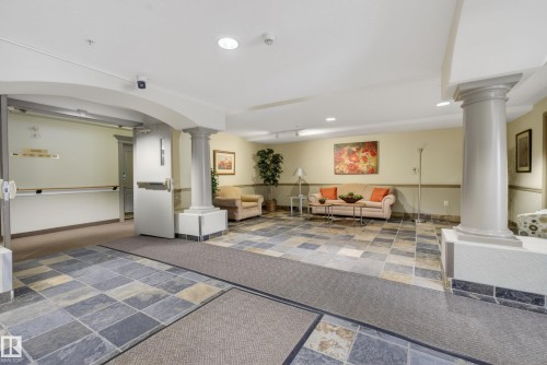 Entry foyer featuring multi-toned slate flooring, architectural columns, a recessed lighting scheme, and an arched entryway - 413 8912 156 Street Nw, Edmonton, AB 