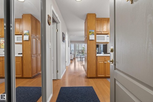 Hardwood-style flooring extends through a hallway with recessed lighting - 413 8912 156 Street Nw, Edmonton, AB 