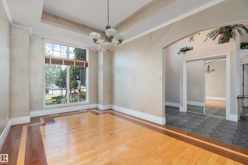 Bright interior space featuring a large picture window, two-tone wood-finish flooring, a decorative chandelier, and an arched entryway - 16103 89 Street, Edmonton, AB - Indoor Photo Showing Other Room